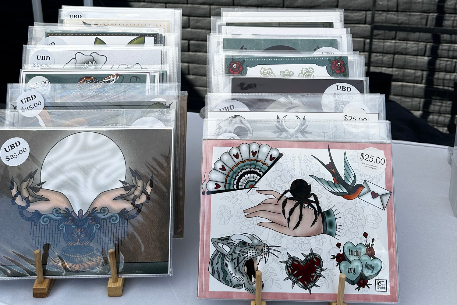 Collection of framed artworks on a table with a textured wall background